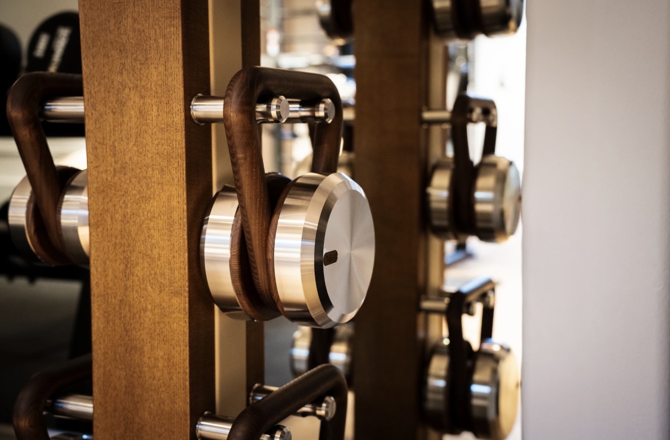Close-up of wood-and-steel dumbbells on a wooden rack at The Hotel Maria.