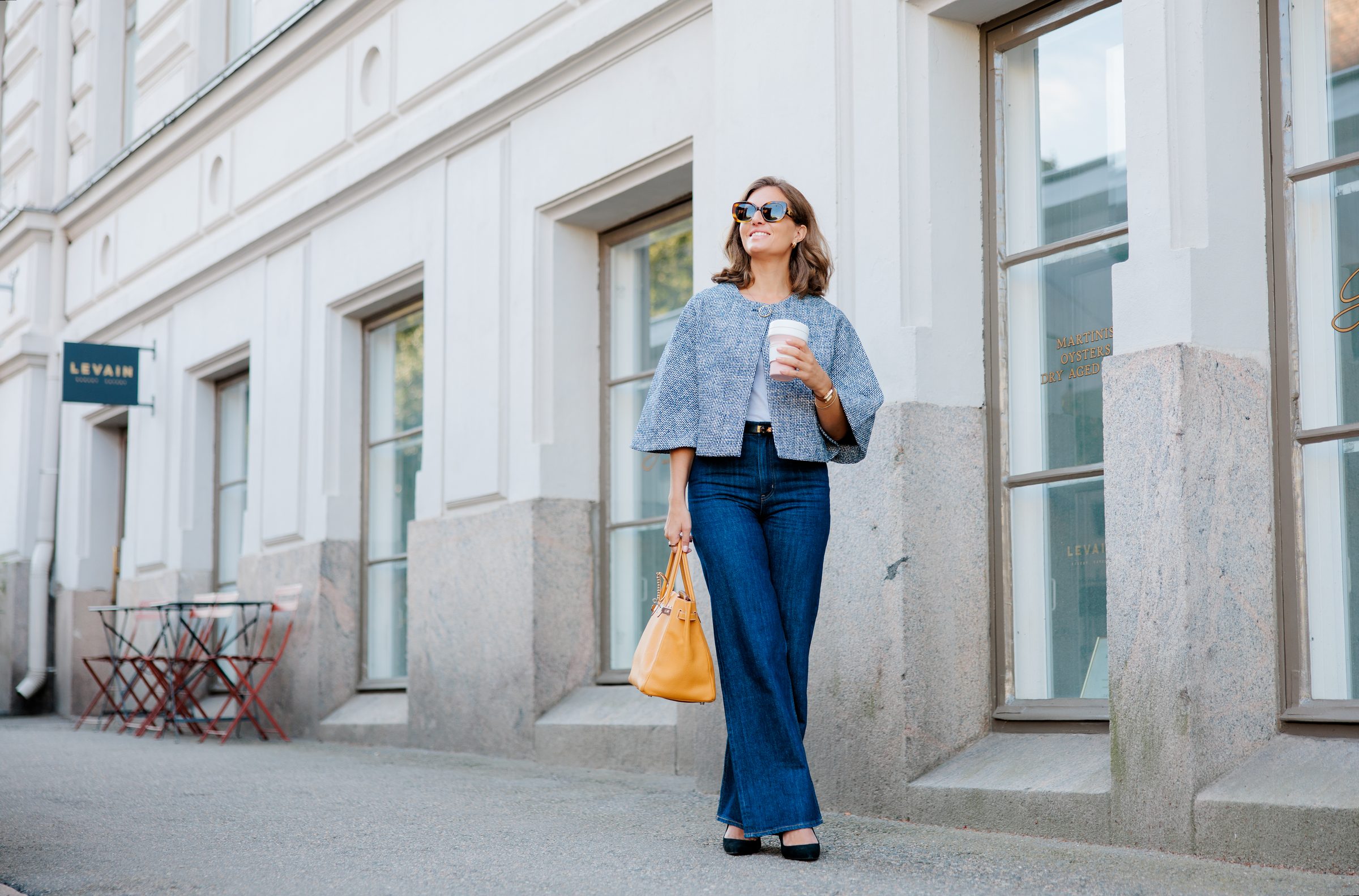 Jenna Toivakka walking past a pale classical façade on a Helsinki street.